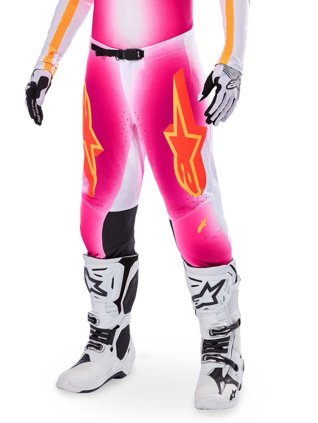 Pantaloni da motocross Alpinestars Supertech AFD MIG Limited Edition, rosa con loghi a stella arancioni e gialli, indossati con stivali da motocross bianchi e guanti bianchi e neri, con pannelli interni alle ginocchia neri e vestibilità atletica, parte di un set da gara ad alte prestazioni