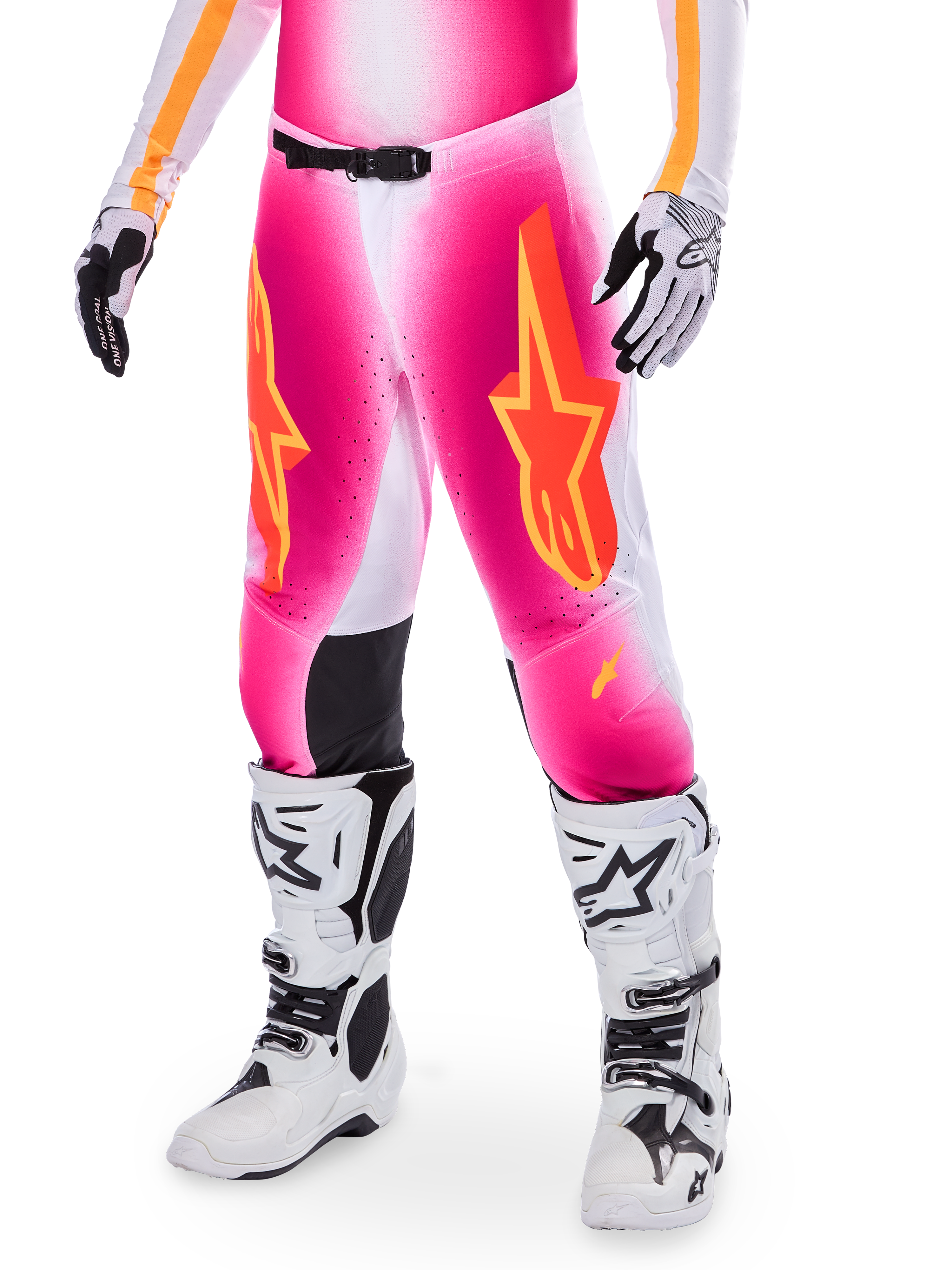 Pantaloni da motocross Alpinestars Supertech AFD MIG Limited Edition, rosa con loghi a stella arancioni e gialli, indossati con stivali da motocross bianchi e guanti bianchi e neri, con pannelli interni alle ginocchia neri e vestibilità atletica, parte di un set da gara ad alte prestazioni