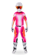 Pilota di motocross che indossa il set Alpinestars Limited Edition Supertech AFD MIG, maglia e pantaloni con sfumatura rosa fluo e bianco e loghi arancioni, casco bianco con occhiali rossi, stivali e guanti bianchi e neri, completo da corsa professionale coordinato.