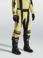 Alpinestars Pantaloni Techstar Atrox, pantaloni da motocross da uomo, giallo e nero, in ripstop elasticizzato 4-way con fibbia magnetica SX2, indossati con stivali e guanti, ideali per competizioni racing off-road.