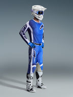 Pilota di motocross che indossa i pantaloni Alpinestars Racer Air Portl 2026 in Ucla Blue White, abbinati a maglia blu e bianca coordinata, casco bianco con occhiali blu e stivali bianchi, set completo per corse off-road.
