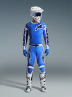 Pantaloni Alpinestars Racer Air Portl 2026, pantaloni da motocross, blu UCLA e bianco, indossati come parte di un set completo da gara con maglia abbinata, casco bianco, maschera blu e stivali bianchi, con pannelli traforati ad alta traspirabilità e loghi evidenti per prestazioni off-road.