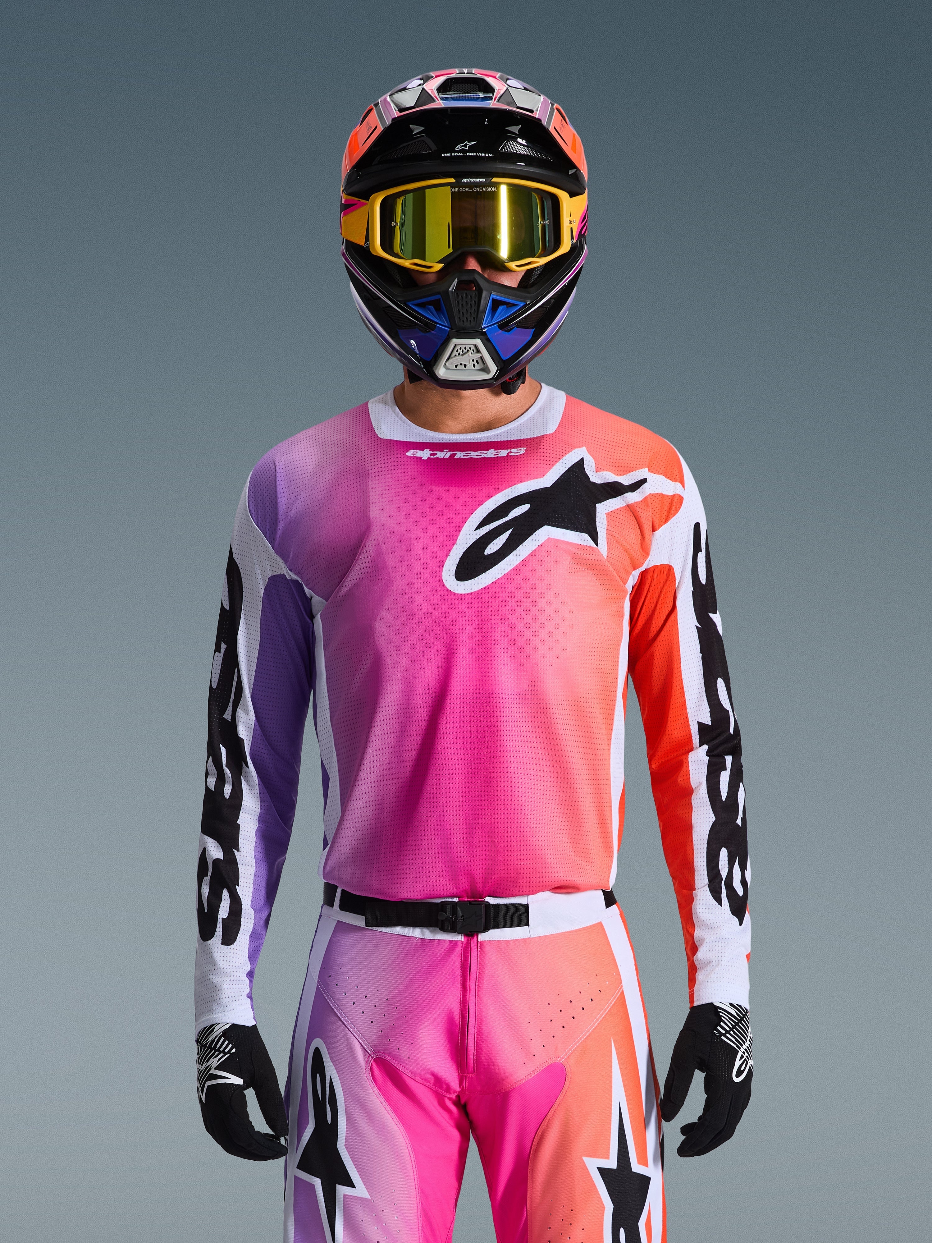 Alpinestars 2026 Racer Air Portl Jersey, maglia da motocross, sfumatura vibrante rosa, viola e arancione, indossata con casco e occhiali coordinati, grande logo a stella nero sul petto, costruzione in mesh traspirante, abbigliamento tecnico per corse fuoristrada