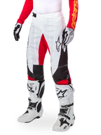 Alpinestars Limited Edition Techstar Deep Pants, pantaloni da motocross, bianco, nero e rosso acceso, indossati con stivali e guanti bianchi e neri, caratterizzati da pannelli frontali bianchi con accenti rossi e dettagli laterali neri, ideati per gare fuoristrada ad alte prestazioni