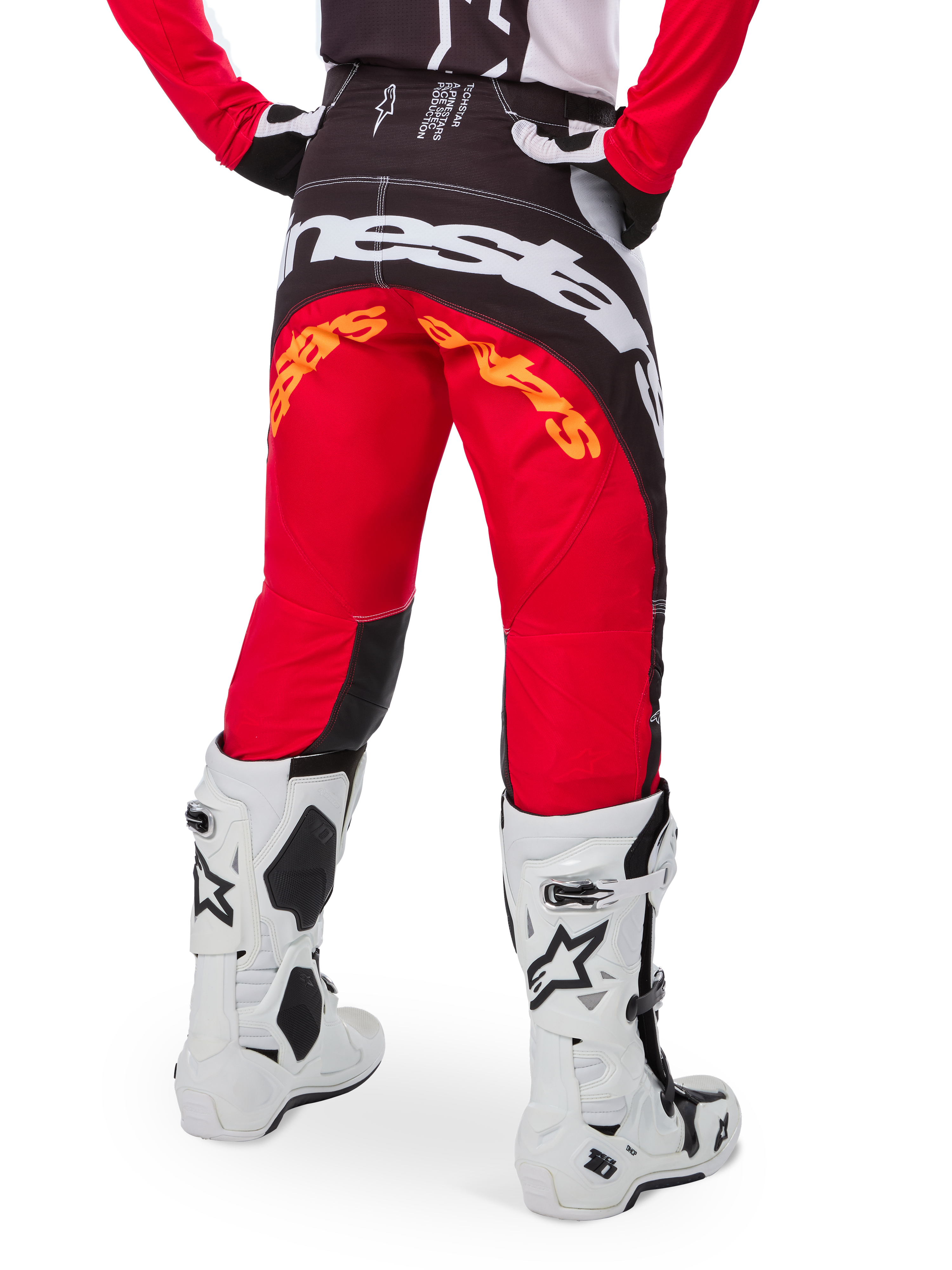 Alpinestars Techstar Deep Pants Edizione Limitata, pantaloni da motocross, nero, bianco e rosso acceso, vista posteriore con grande logo Alpinestars bianco sulla seduta e dettagli arancioni, indossati con stivali tecnici bianchi per competizioni fuoristrada professionistiche.