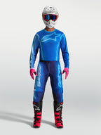 Alpinestars Pantaloni Fluid Kepler, pantaloni da motocross da uomo, blu, in poliestere 600D resistente e pannelli elasticizzati, indossati con casco e stivali da fuoristrada.