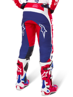 Pantaloni Alpinestars Limited Edition Techstar Fortitude, pantaloni da motocross, rosso, bianco e blu, vista posteriore indossati con stivali coordinati rossi e bianchi, con loghi a stella bianchi sulle cosce, design multi-pannello resistente per gare off-road professionali