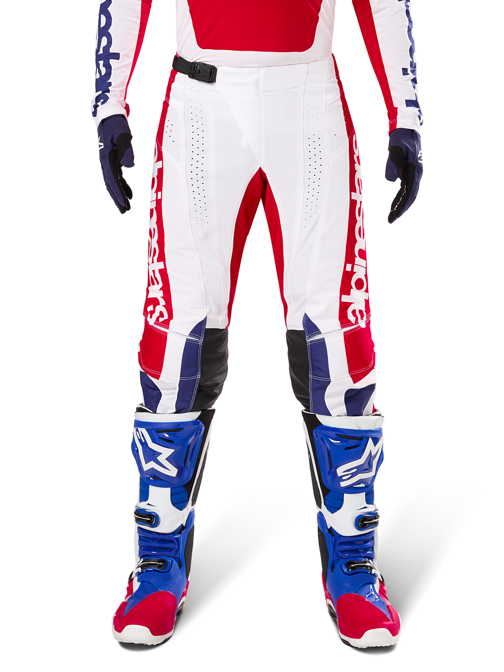 Alpinestars Limited Edition Techstar Fortitude Pants, pantaloni da motocross, rosso acceso, bianco e blu, indossati con equipaggiamento coordinato comprensivo di stivali protettivi e guanti blu, base bianca con grafiche rosse, pannelli sulle ginocchia in pelle nera e perforazioni al laser, abbigliamento professionale da gara fuoristrada