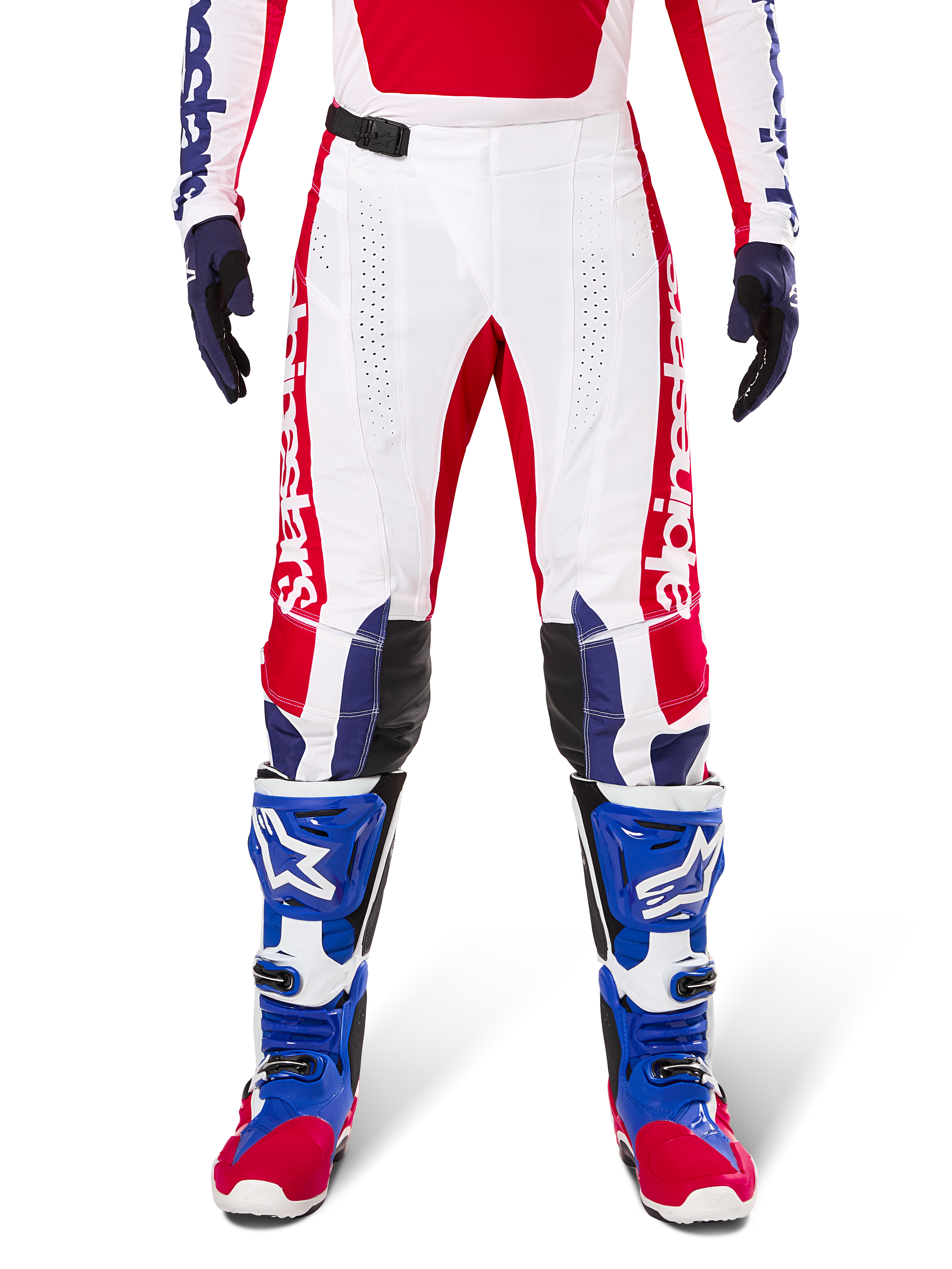 Alpinestars Limited Edition Techstar Fortitude Pants, pantaloni da motocross, rosso acceso, bianco e blu, indossati con equipaggiamento coordinato comprensivo di stivali protettivi e guanti blu, base bianca con grafiche rosse, pannelli sulle ginocchia in pelle nera e perforazioni al laser, abbigliamento professionale da gara fuoristrada