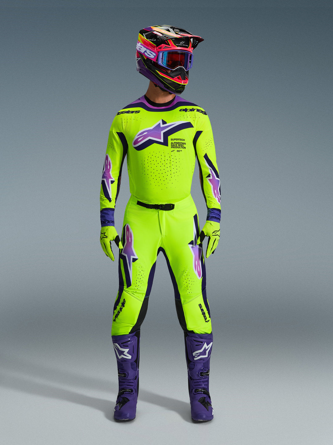 Alpinestars 2026 Supertech Vista Gear Set, completo da motocross giallo neon e viola, comprensivo di casco multicolore coordinato, maglia e pantaloni con loghi viola e bianchi, stivali viola e guanti per corse fuoristrada