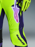 Alpinestars 2026 Supertech Vista Pants, pantaloni da motocross, giallo, viola e nero, primo piano con logo a stella sfumato e fori di ventilazione tagliati al laser, abbinati a guanti da corsa coordinati