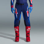Alpinestars 2026 Supertech Vista Gear Set, pantaloni da motocross in blu navy e blu brillante con loghi rossi e bianchi, abbinati a guanti azzurri e stivali da motocross rosso acceso, abbigliamento da gara professionale.