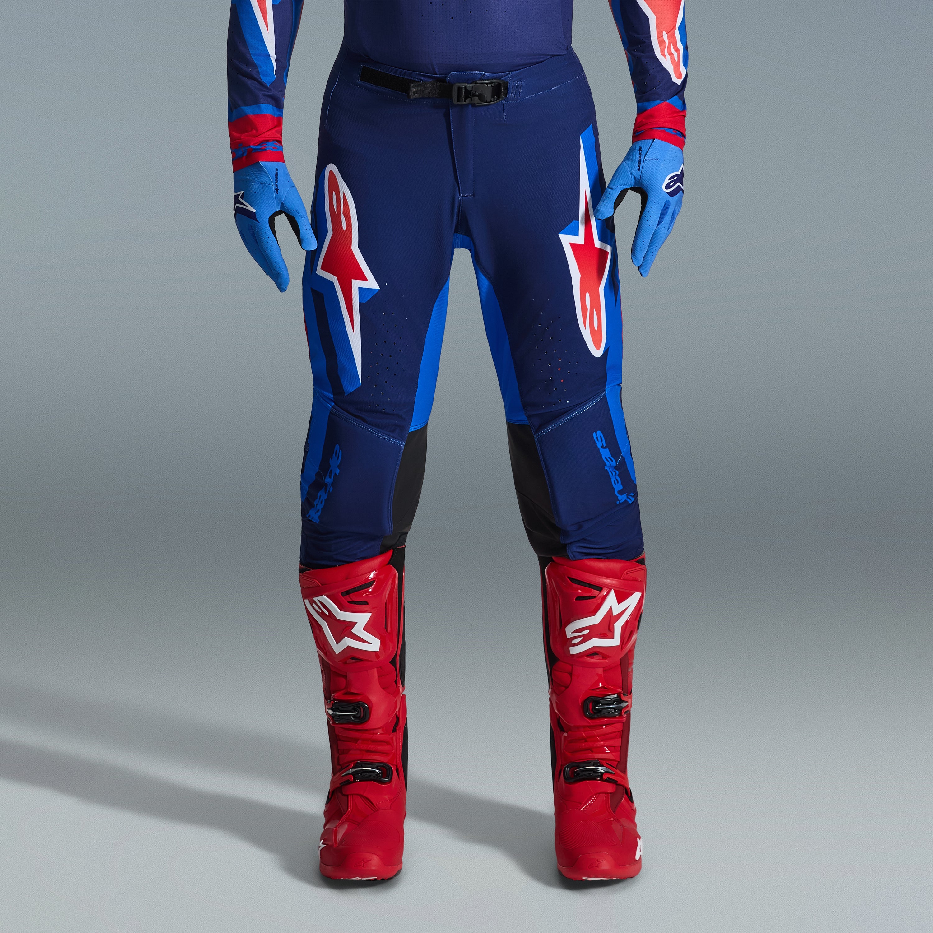 Alpinestars 2026 Supertech Vista Gear Set, pantaloni da motocross in blu navy e blu brillante con loghi rossi e bianchi, abbinati a guanti azzurri e stivali da motocross rosso acceso, abbigliamento da gara professionale.