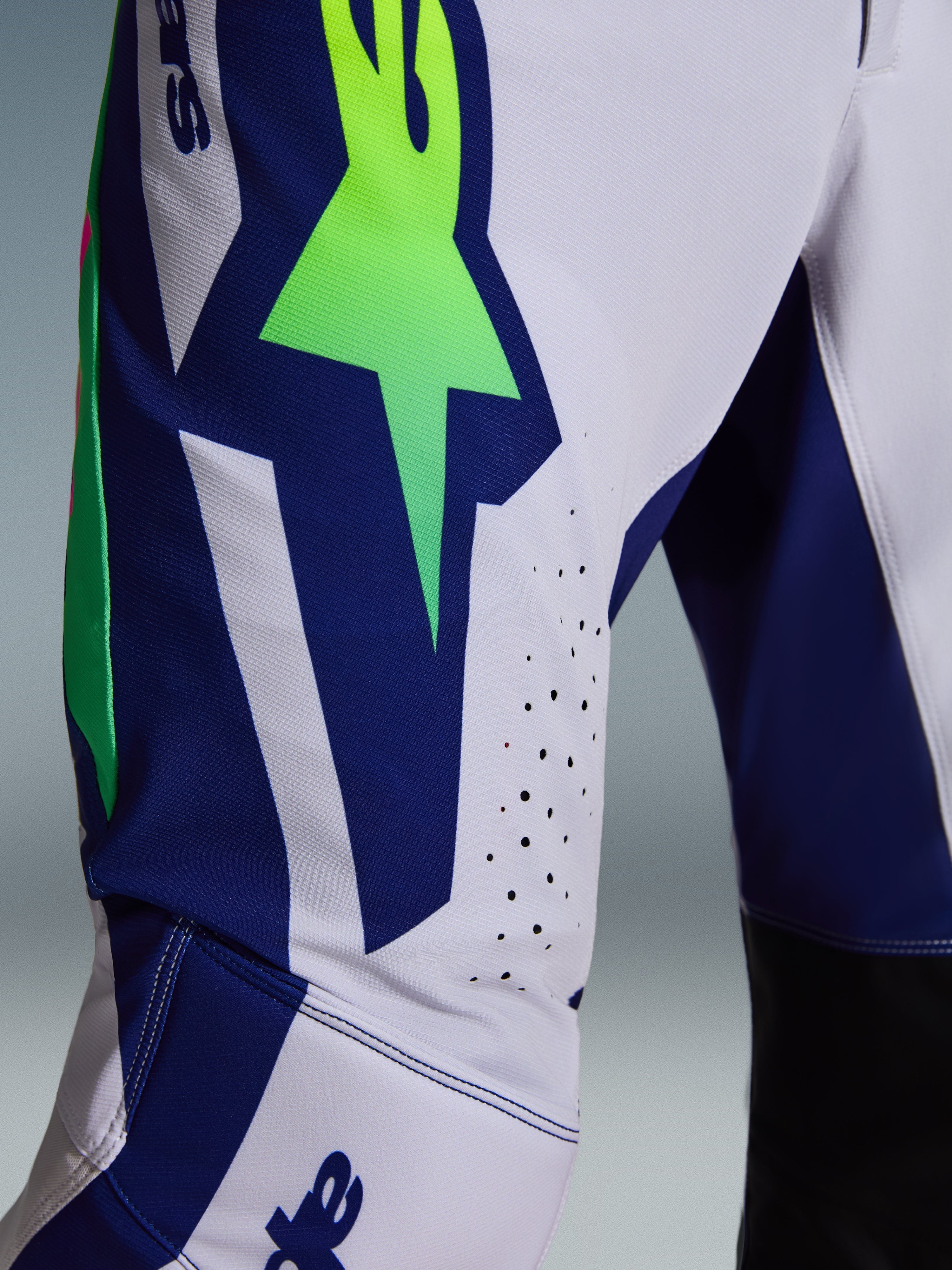Alpinestars Supertech Vista Pants 2026, pantaloni da motocross, grigio chiaro con accenti giallo fluo e blu, vista ravvicinata della coscia con grande logo A-star, fori di ventilazione tagliati al laser e tessuto rip-stop elasticizzato.