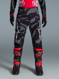 Alpinestars Pantaloni Techstar Beast Coast edizione limitata, pantaloni da motocross con motivo camouflage nero e grigio, indossati con guanti e stivali coordinati neri e arancioni, abbigliamento tecnico per off-road