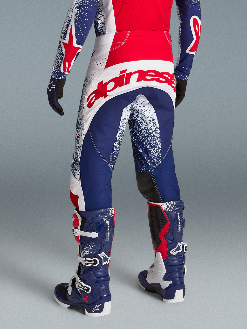 Alpinestars Techstar Unity Pantaloni, abbigliamento motocross racing rosso, bianco e blu, grande logo posteriore, indossati.