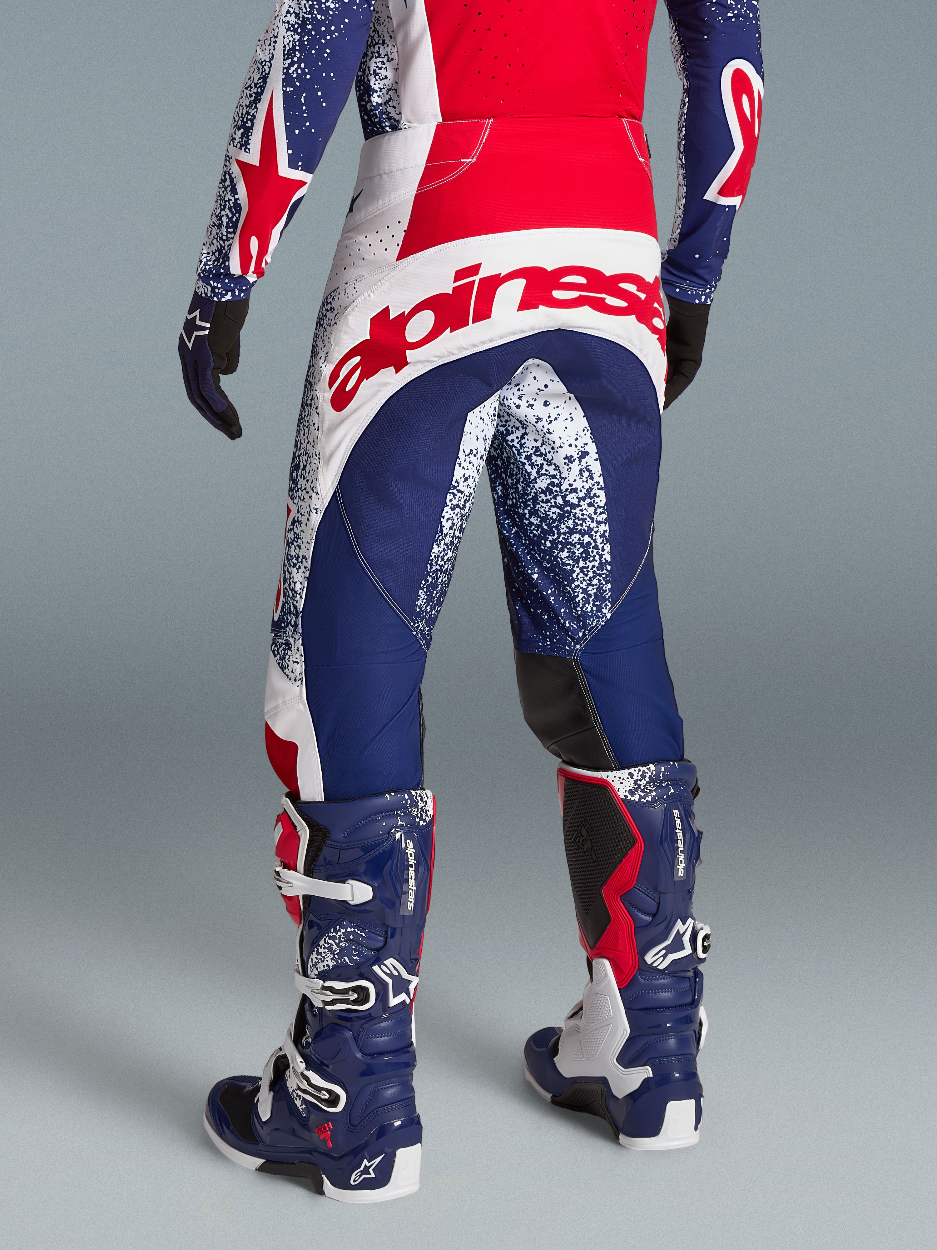 Alpinestars Techstar Unity Pantaloni, abbigliamento motocross racing rosso, bianco e blu, grande logo posteriore, indossati.