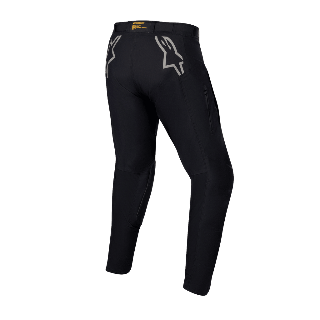 Alpinestars Techdura Pants, pantaloni da enduro e off-road neri, vista posteriore con loghi a stella grigi sui fianchi, marchio giallo sulla fascia in vita posteriore, robusto materiale in poliammide elasticizzata con design resistente per la guida in moto