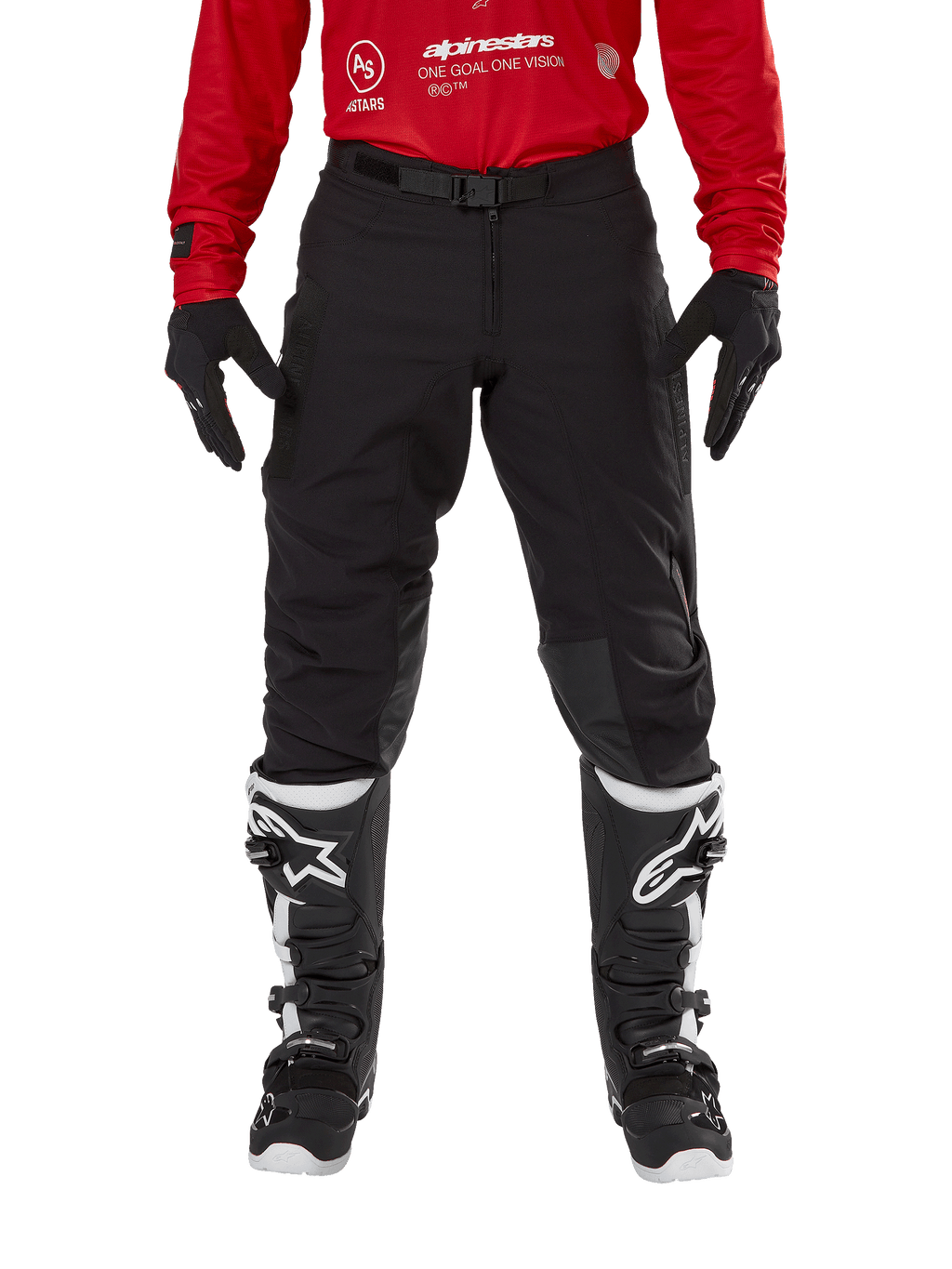 Pantaloni Alpinestars Techdura, pantaloni da enduro e off-road, nero, indossati con una maglia Alpinestars rossa e stivali bianchi e neri, caratterizzati da una robusta costruzione in tela elasticizzata, fibbia magnetica regolabile e rinforzi in pelle sulle ginocchia per prestazioni fuoristrada.