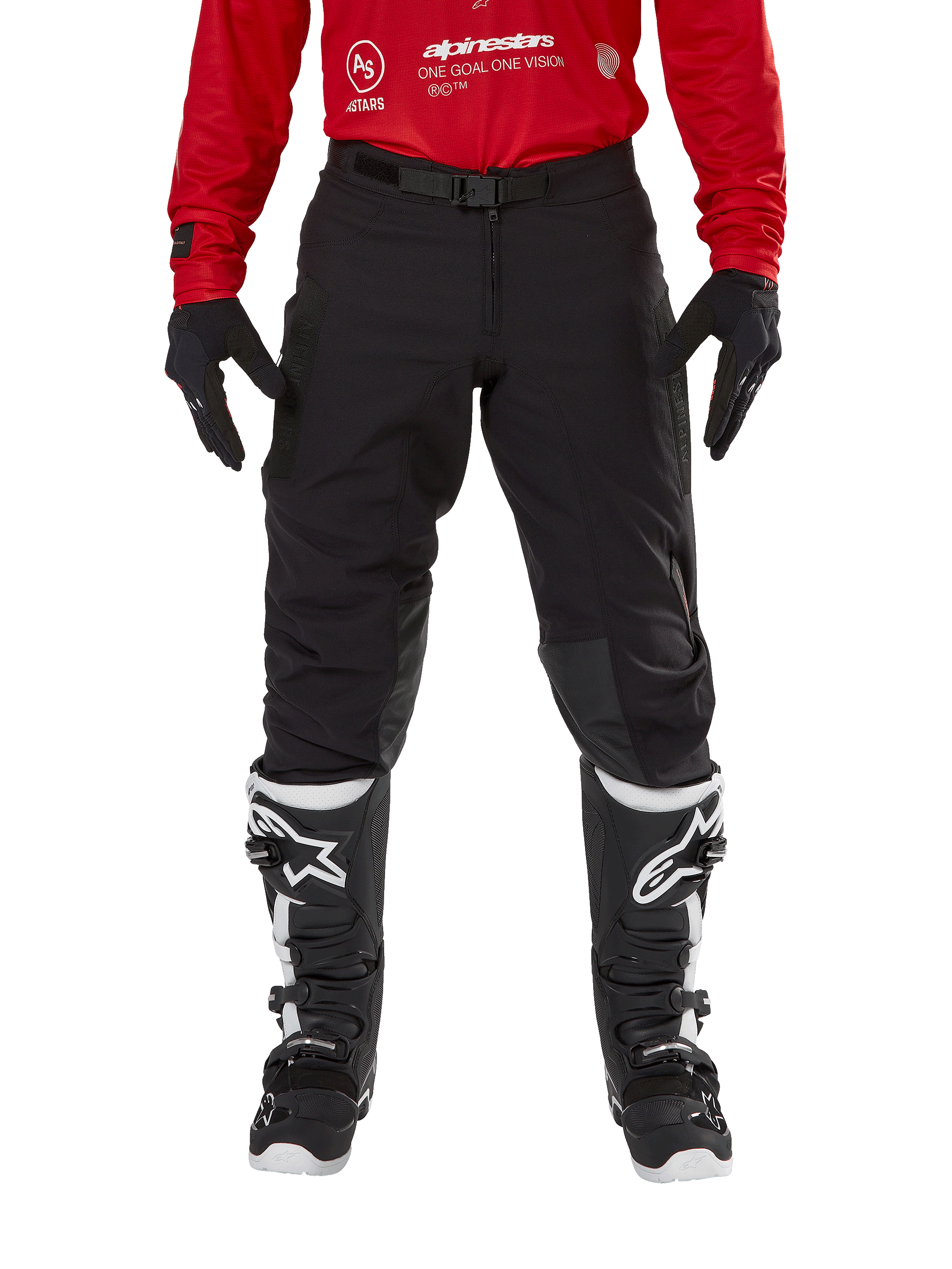 Pantaloni Alpinestars Techdura, pantaloni da enduro e off-road, nero, indossati con una maglia Alpinestars rossa e stivali bianchi e neri, caratterizzati da una robusta costruzione in tela elasticizzata, fibbia magnetica regolabile e rinforzi in pelle sulle ginocchia per prestazioni fuoristrada.