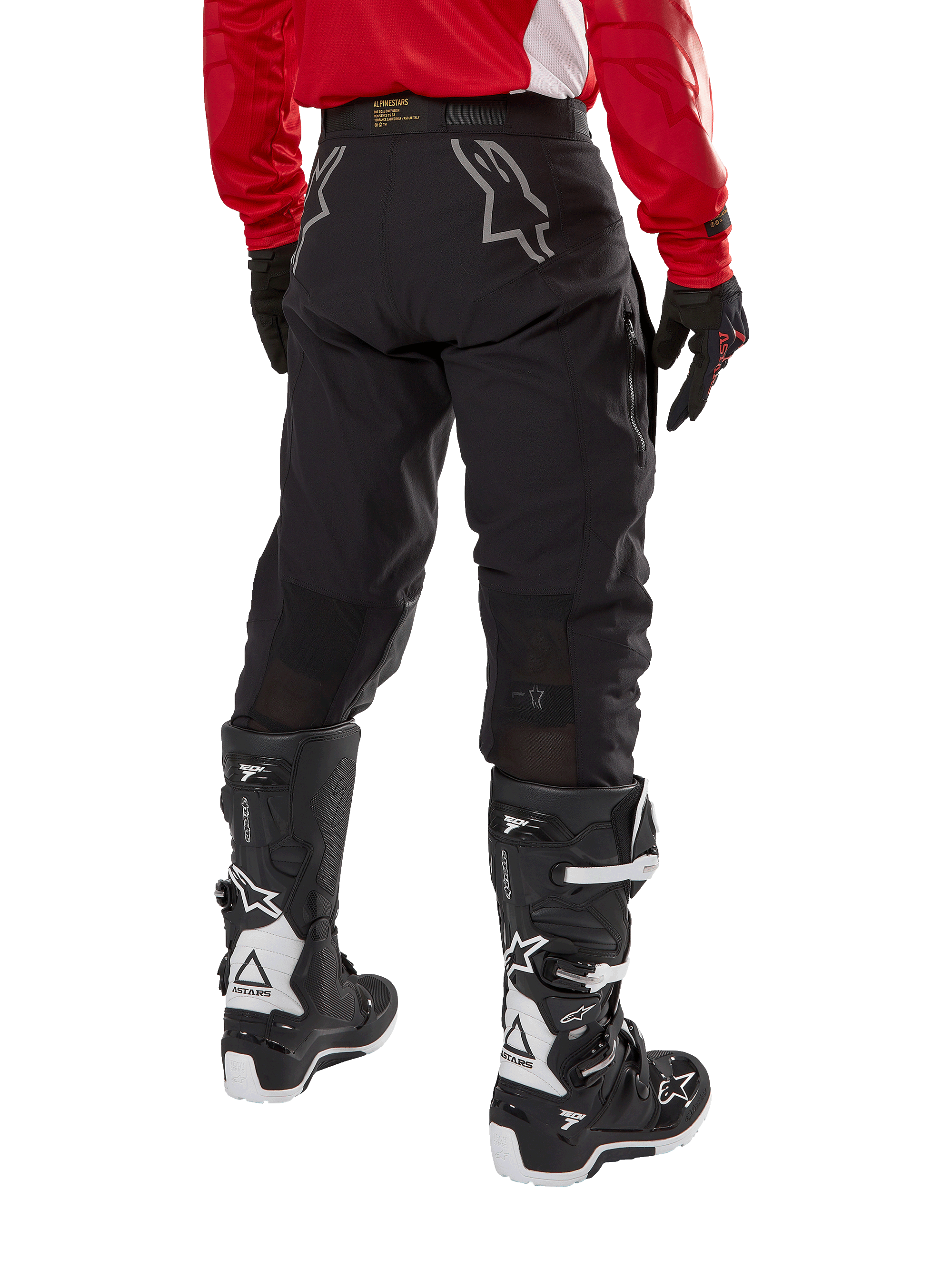 Pantaloni Alpinestars Techdura, pantaloni da enduro fuoristrada, nero, vista posteriore con loghi a stella grigi sulla seduta, indossati con maglia rossa a maniche lunghe e stivali Tech 7 neri e bianchi, robusta costruzione in tessuto per guida adventure