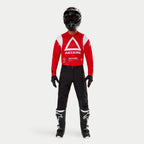 Alpinestars Techdura Pants, pantaloni da enduro e off-road, nero, indossati con maglia a maniche lunghe Astars rossa e bianca, casco nero e stivali neri e bianchi, caratterizzati da una robusta costruzione in poliammide elasticizzata e pannelli tecnici per la guida off-road.