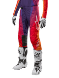 Alpinestars 2024 Techstar Pneuma Pants, pantaloni da motocross, viola profondo con accenti arancione e blu scuro, logo Alpinestars bianco, equipaggiamento protettivo per fuoristrada, indossati con stivali bianchi e guanti