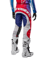 Alpinestars Pantaloni Techstar Pneuma 2024, pantaloni da motocross, Blu Mars Rosso Bianco, vista posteriore indossati con maglia coordinata e stivali bianchi, con logo bianco sulla seduta e pannelli multicolore, abbigliamento professionale da motocross