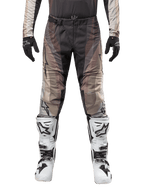 Pantaloni Alpinestars Techstar Pneuma 2024, pantaloni da motocross, grigio Dark Sand Iron Dust, indossati con maglia coordinata, guanti neri e stivali bianchi e neri, con fibbia magnetica SX2 e logo Astars, abbigliamento resistente per gare fuoristrada