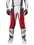 Alpinestars Techstar Ocuri Pants 2024, pantaloni da motocross, rosso Mars, bianco e nero, vista frontale indossati con maglia bianca coordinata, guanti neri e stivali bianchi, caratterizzati da pannelli traforati traspiranti e un taglio d'ispirazione racing per prestazioni fuoristrada.