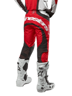 Alpinestars 2024 Techstar Ocuri Pants, pantaloni da motocross, Mars Red, bianco e nero, vista posteriore con grande logo Alpinestars bianco sulla seduta, pannelli di ventilazione in mesh nero, indossati con stivali da motocross bianchi e neri, design atletico race-fit per la guida off-road