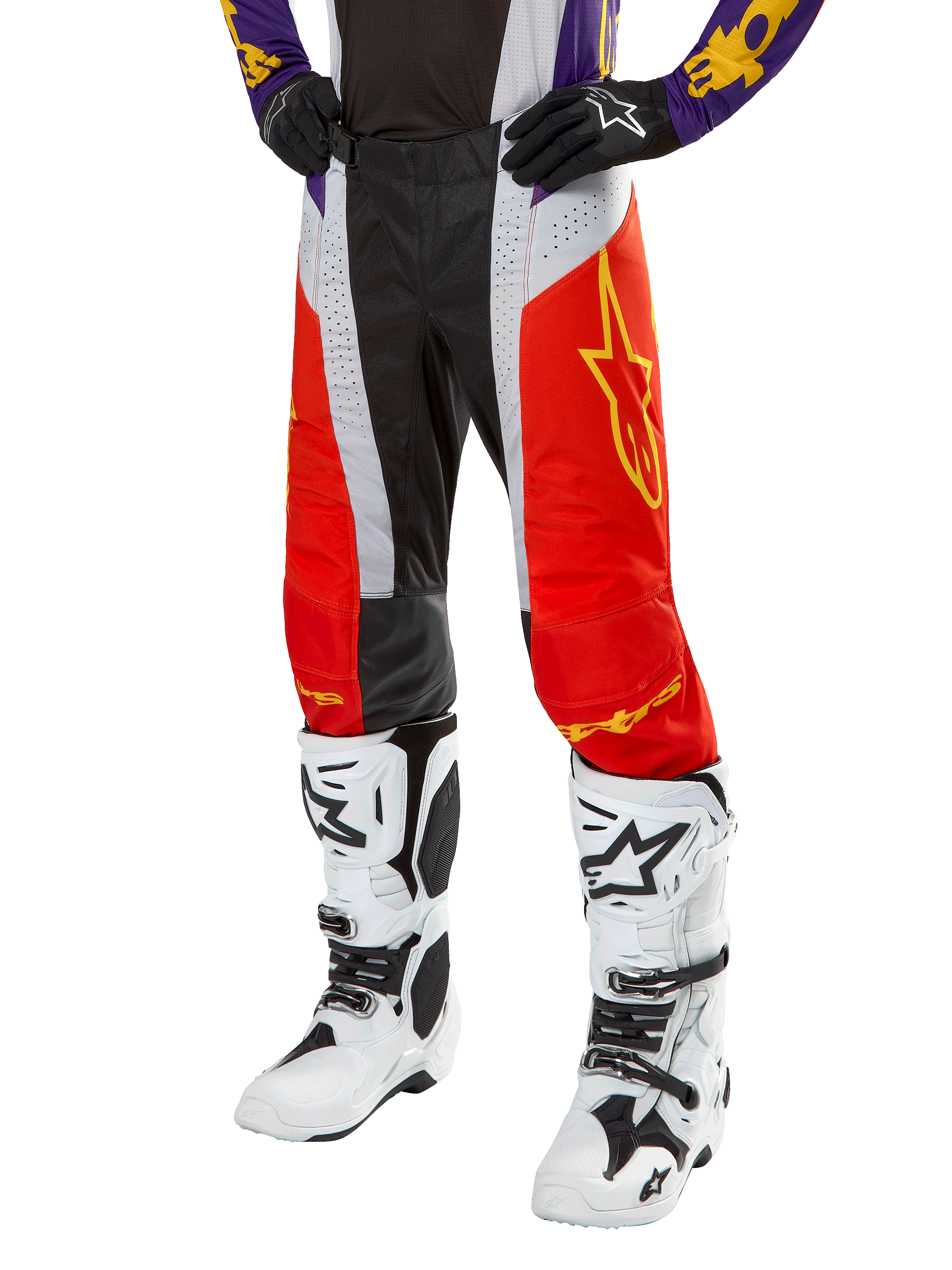 Alpinestars 2024 Techstar Ocuri Pants, pantaloni da motocross, arancione acceso, nero e bianco con grafica a stella gialla, indossati con maglia viola e stivali bianchi, abbigliamento tecnico resistente per competizioni fuoristrada