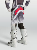 Alpinestars Pantaloni Supertech Swan Ragazzo, pantaloni motocross grigi e bianchi con logo rosso, vista posteriore su modello.