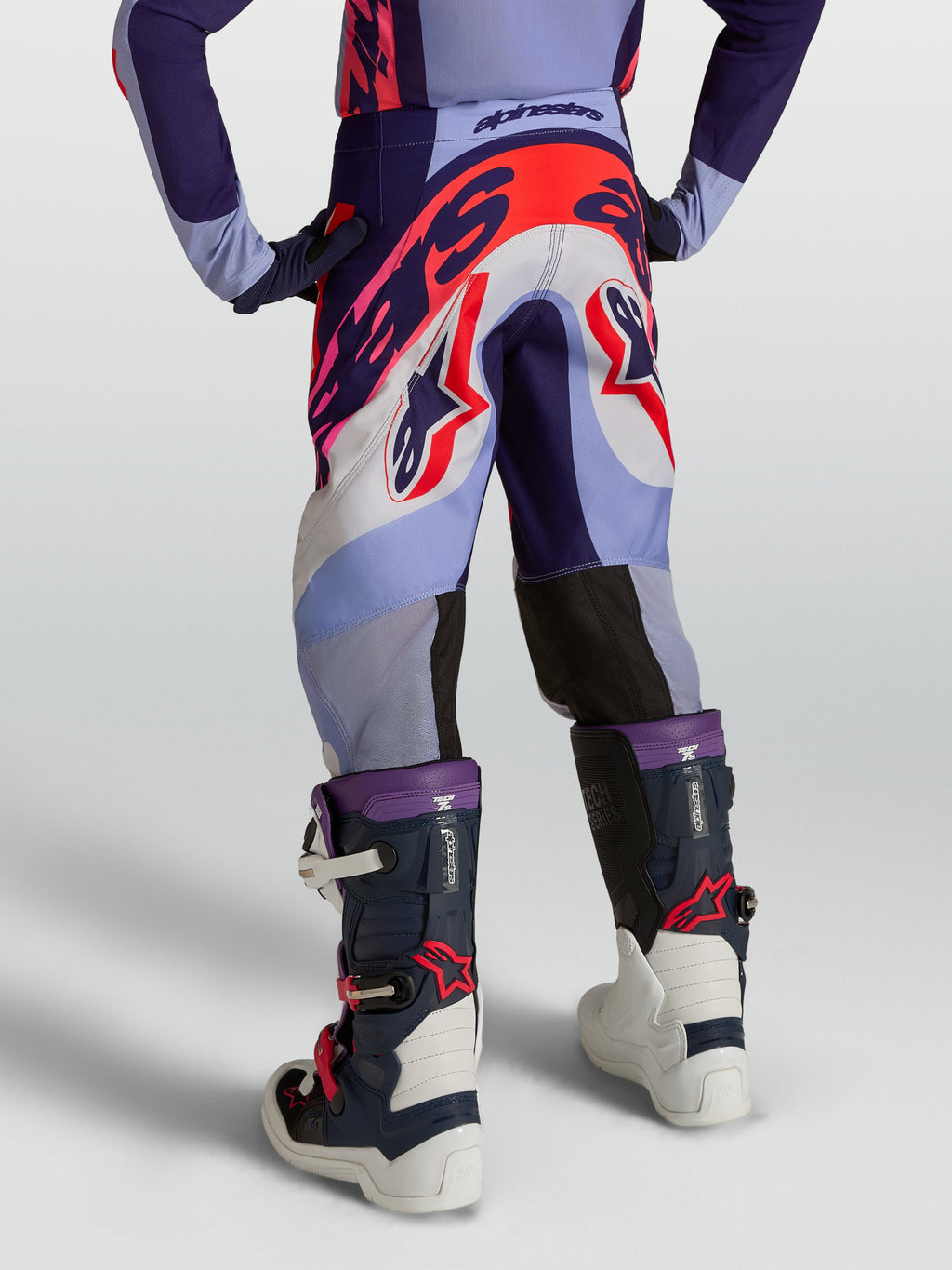 Alpinestars Pantaloni Supertech Dyna Ragazzo, pantaloni da motocross per ragazzi, viola e rosa fluo, tessuto rip-stop elasticizzato, vista posteriore con stivali, protezione racing fuoristrada