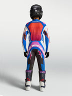 Alpinestars Pantaloni Supertech Maven Ragazzo, pantaloni da motocross per giovani, blu e rosa corallo, vestibilità atletica da gara, vista posteriore su giovane pilota