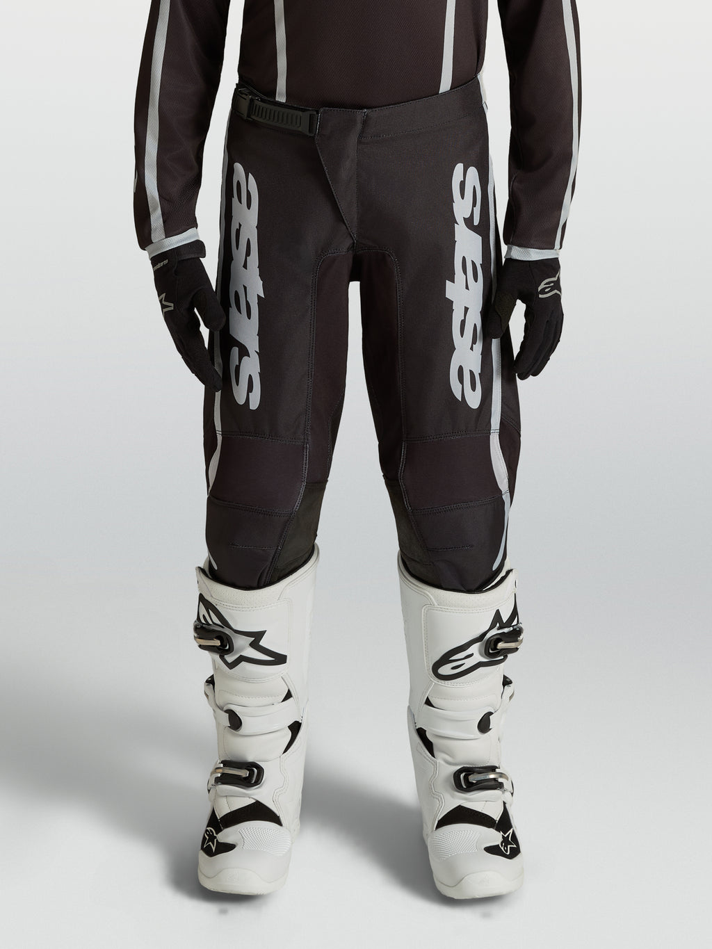 Pantaloni motocross Alpinestars Fluid Apex V2 Ragazzo, neri e argento, in polytessuto 600D con gambe precurvate.