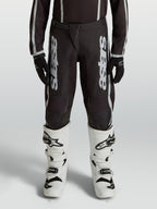 Pantaloni motocross Alpinestars Fluid Apex V2 Ragazzo, neri e argento, in polytessuto 600D con gambe precurvate.