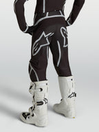 Alpinestars pantaloni Fluid Apex V2 ragazzo, motocross neri e argento, vista posteriore con stivali bianchi