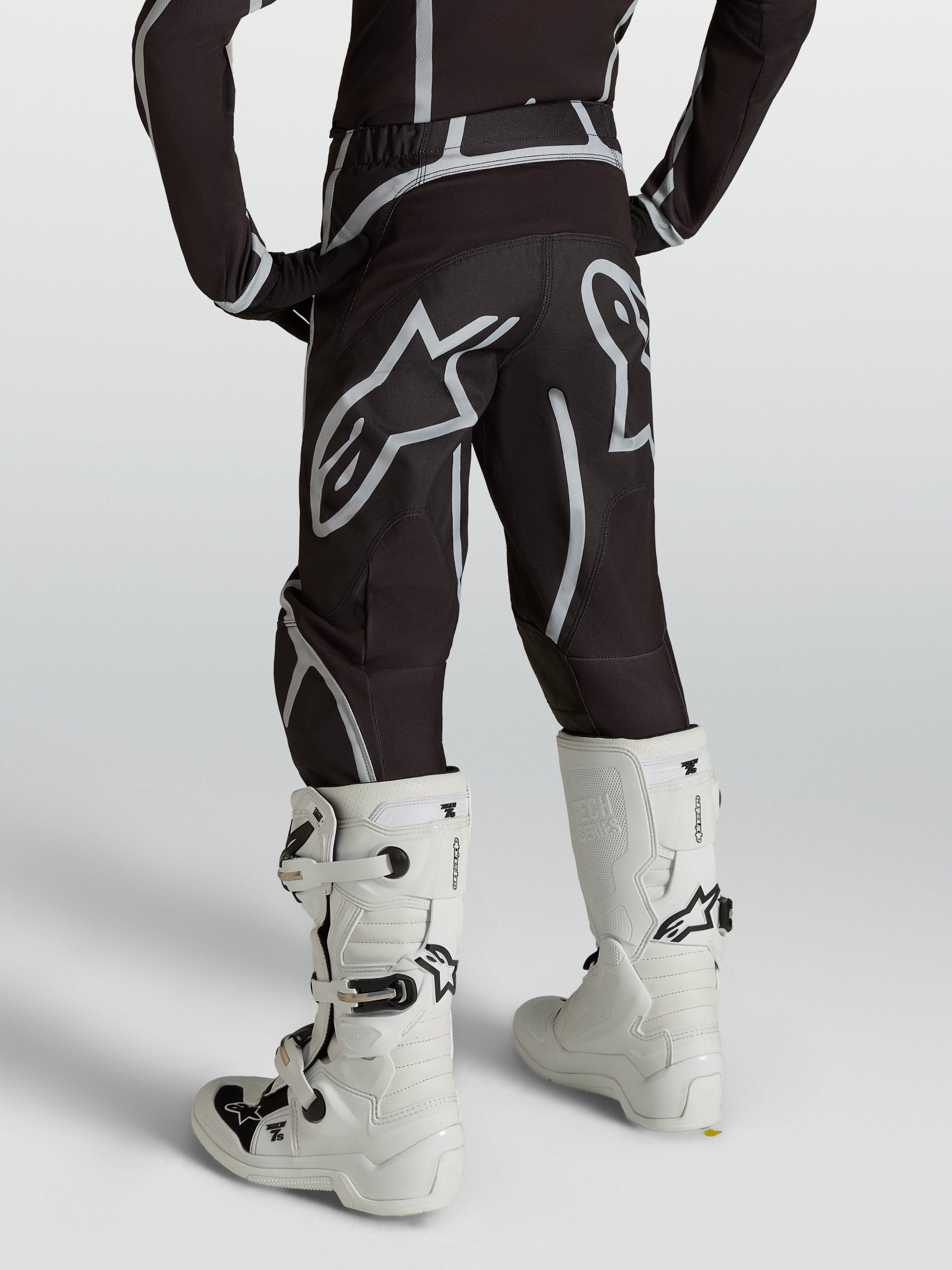 Alpinestars pantaloni Fluid Apex V2 ragazzo, motocross neri e argento, vista posteriore con stivali bianchi