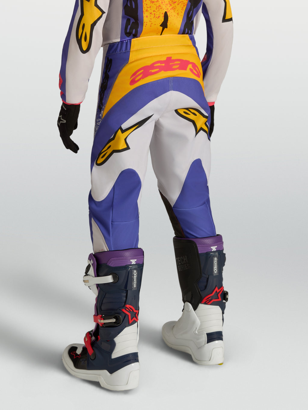 Alpinestars Pantaloni Fluid Drag Ragazzo, pantaloni da motocross blu e bianchi con grafica gialla, vista posteriore, costruzione ergonomica in poliestere 600D per off-road