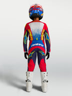 Alpinestars pantaloni Fluid Drag Ragazzo, completo da motocross per ragazzi, blu e rosso, vista posteriore con maglia coordinata e stivali bianchi.