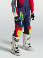 Alpinestars pantaloni Fluid Drag ragazzo 2027, completo motocross blu navy e rosso con dettagli neon e stivali bianchi.