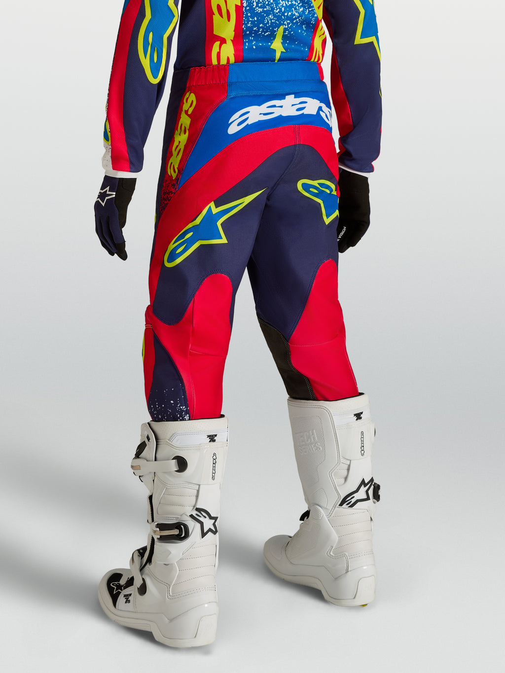 Alpinestars Pantaloni Fluid Drag Ragazzo, pantaloni da motocross blu navy e rosso fuoco, vista posteriore con stivali bianchi