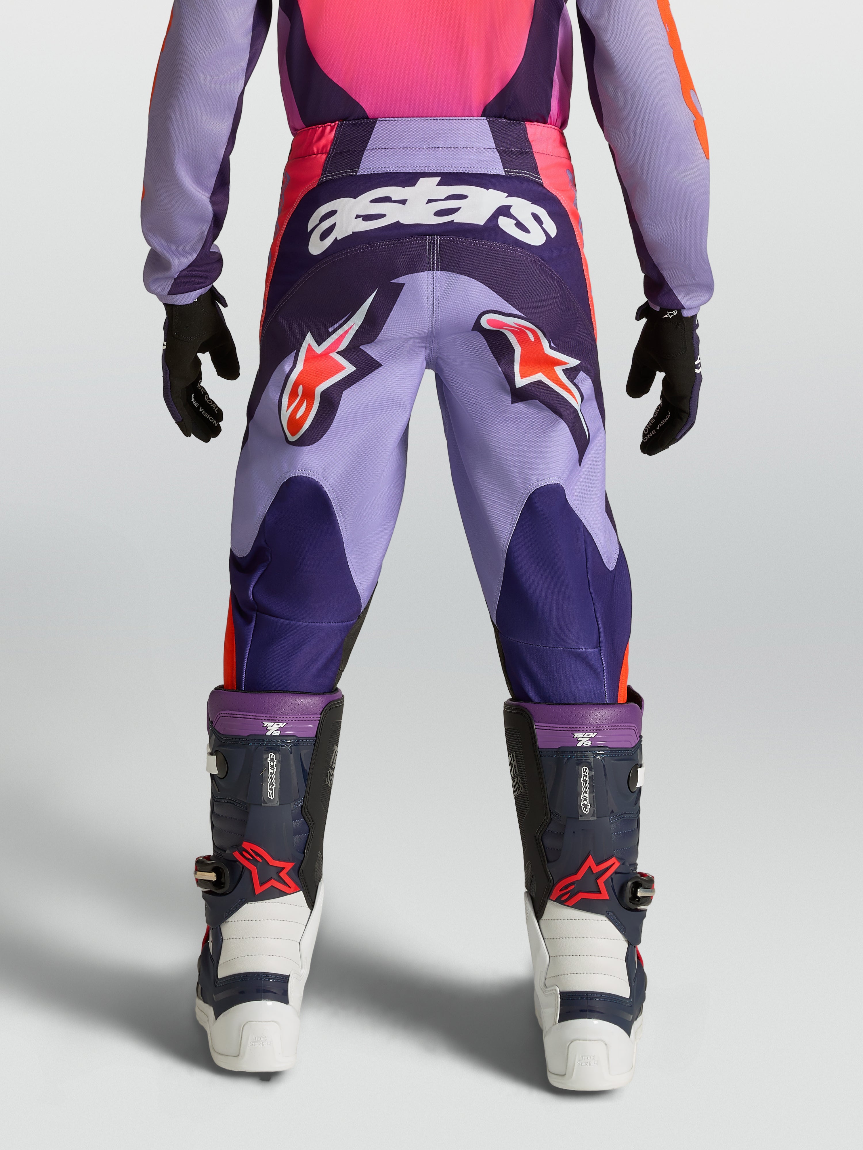 Alpinestars Pantaloni Fluid Hunt Ragazzo, pantaloni da motocross fuoristrada, viola e rosa, loghi a stella rossi e scritta astars bianca, costruzione in poliestere resistente, vista posteriore su modello.