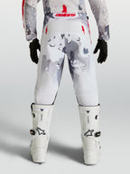 Alpinestars Pantaloni Fluid Lone Ragazzo, pantaloni da motocross per ragazzi, grigio camouflage e bianchi con dettagli rossi, vista posteriore su pilota.