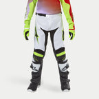Alpinestars pantaloni Youth Racer Lucent 2024, pantaloni da motocross, bianco con accenti giallo neon e nero, indossati con guanti neon coordinati e stivali neri, con gambe pre-curvate ergonomiche e loghi Alpinestars, equipaggiamento ad alte prestazioni per corse fuoristrada