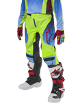 Pantaloni Alpinestars Youth 2024 Racer Hoen, pantaloni da motocross, giallo fluo e blu notte con dettagli rossi, indossati con guanti coordinati e stivali bianchi, neri e rossi, con vestibilità sportiva e gambe pre-curvate per il fuoristrada