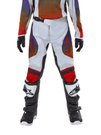 Alpinestars pantaloni Youth Racer Hoen 2024, pantaloni da motocross per ragazzi, grigio chiaro, arancione acceso e nero, indossati con maglia coordinata e stivali da motocross bianchi e neri, loghi Alpinestars rossi su cosce e ginocchia, design sportivo per il fuoristrada