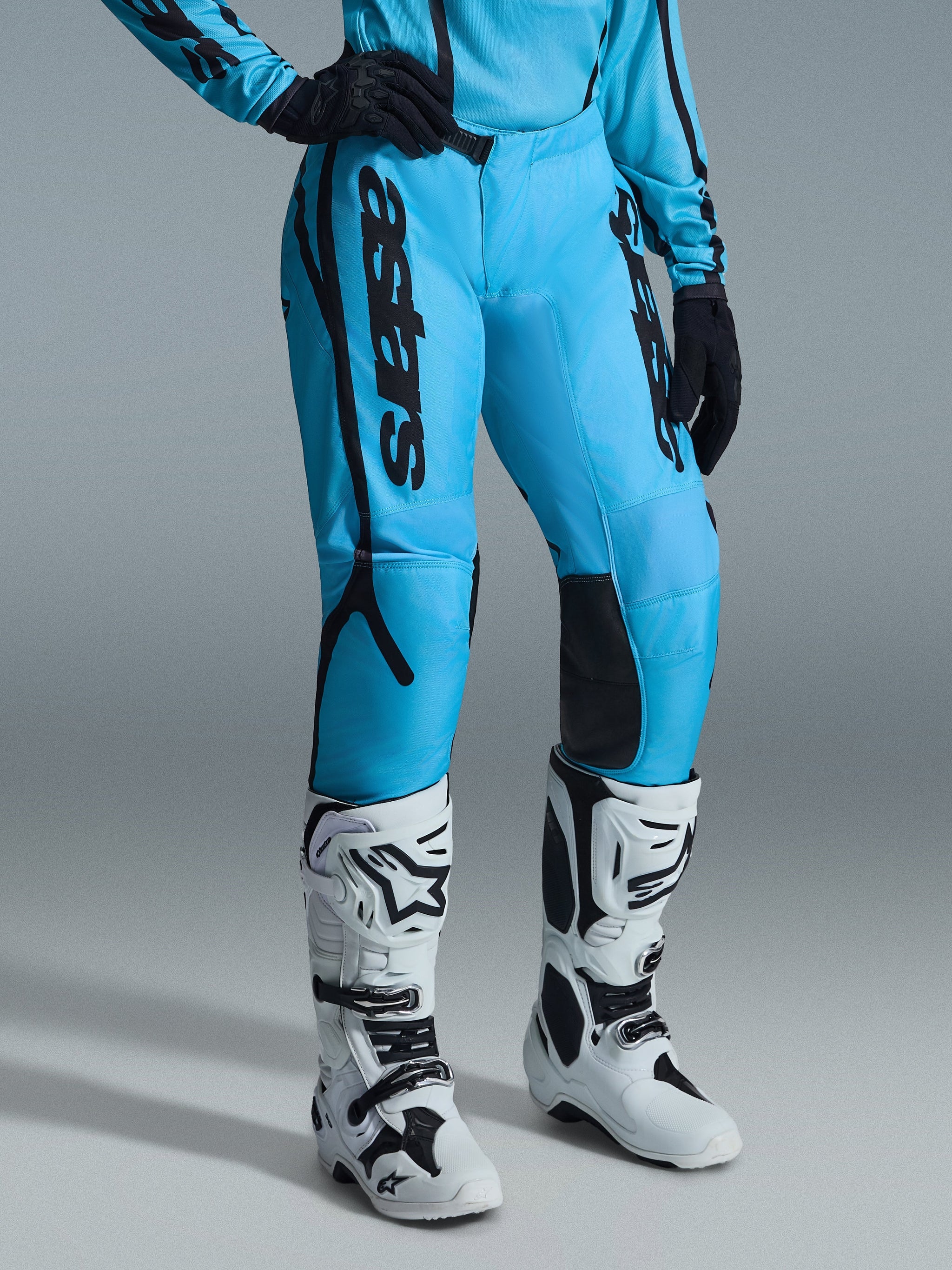 Alpinestars Stella Fluid Apex Pants 2026 da donna, pantaloni da motocross, blu acceso con branding nero, indossati con maglia coordinata, guanti neri e stivali da fuoristrada bianchi e neri, design ergonomico per prestazioni di guida