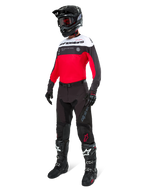 Alpinestars Pro-Dura Jersey, maglia da motocross ed enduro, nero, rosso brillante e bianco, indossata con pantaloni neri, casco nero e stivali bianchi e neri, caratterizzata da logo evidente sul petto e perforazioni laser, equipaggiamento ad alte prestazioni per il fuoristrada